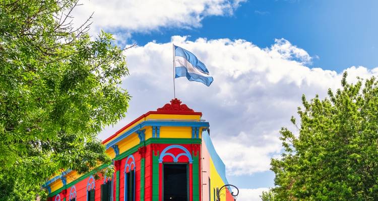 A colorful building with an Argentine flag against a bright blue sky.