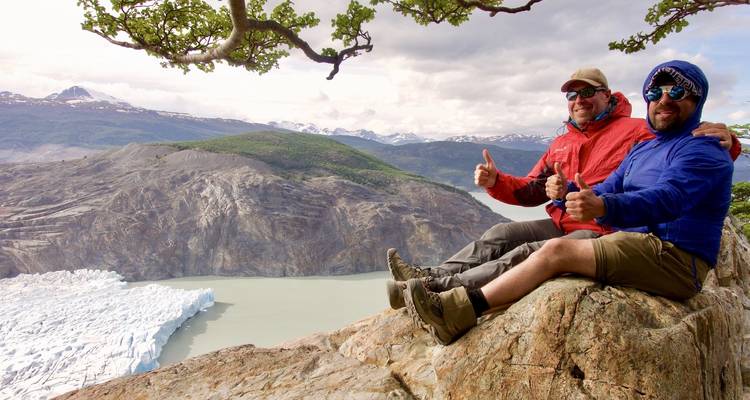 Dos personas dando pulgares arriba con vista a un glaciar.