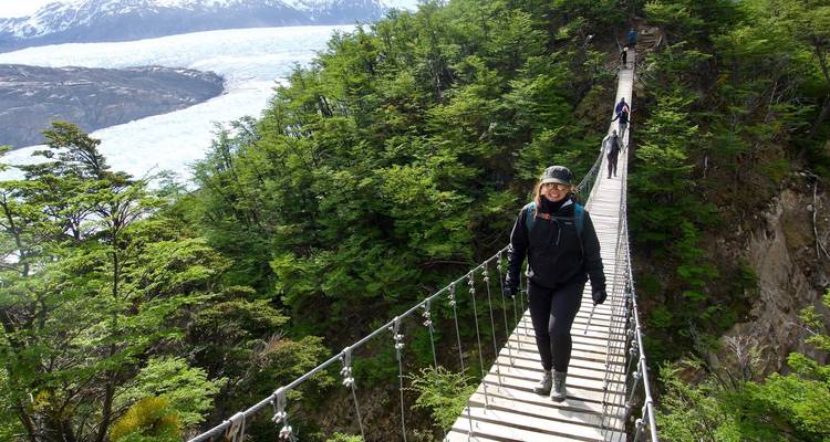 Excursionistas cruzando un puente estrecho en zona boscosa.