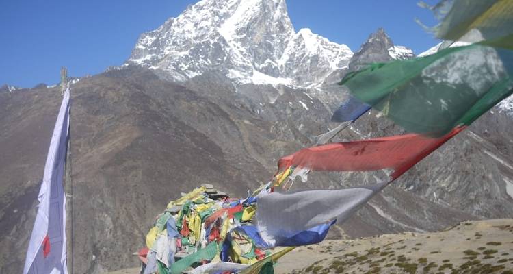 Des drapeaux de prière colorés flottent avec un pic enneigé escarpé se dressant dans un ciel bleu limpide