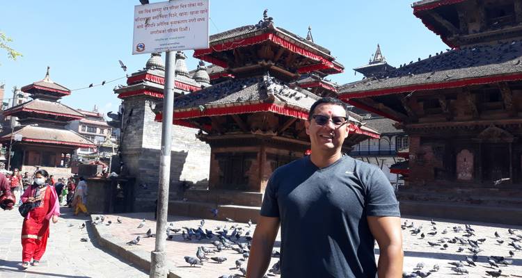 Le voyageur pose parmi les temples pagodes aux toits rouges remplis de pigeons à Kathmandu Durbar Square.