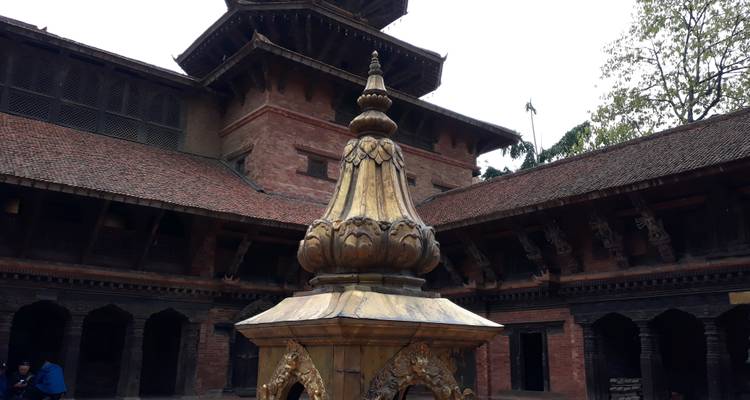 Elaborate golden finial in the courtyard of a red-brick palace complex