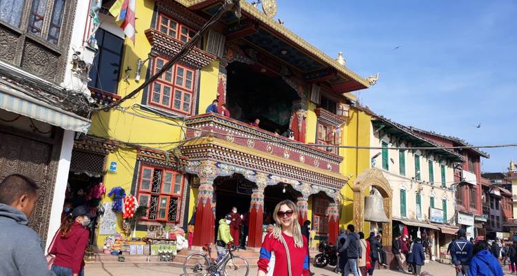Bustling street outside a brightly painted Tibetan Buddhist monastery in Kathmandu with tourists and locals.