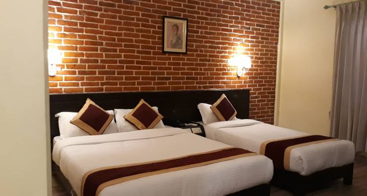Hotel room with two beds and a brick wall.