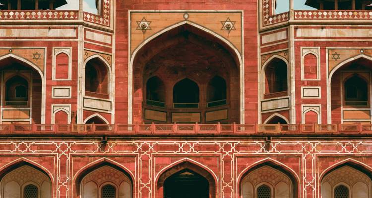 Facade of a historic building with large arches and red stone