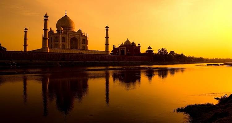 Sonnenuntergangsblick auf das Taj Mahal, das sich im Fluss spiegelt.