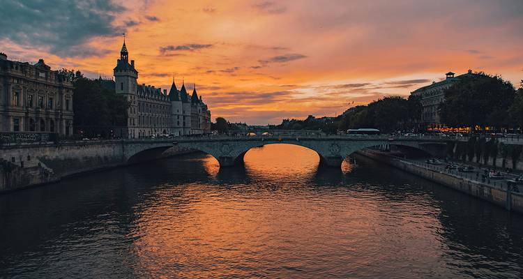 Coucher de soleil dramatique d'un orange éclatant sur la Seine avec le skyline parisien et les reflets du pont de pierre