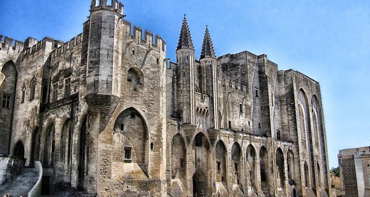 Massive stone Gothic palace with pointed towers and arched windows under a clear sky.