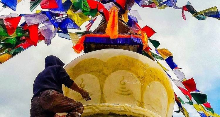 Man painting a stupa with prayer flags.