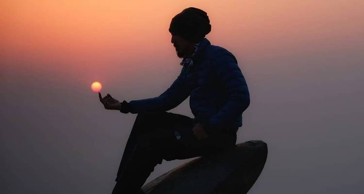 Silhouette of a man holding the setting sun.
