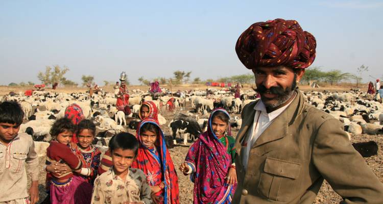 Rajasthani Mann mit einer Gruppe von Kindern und Schafen im Hintergrund.