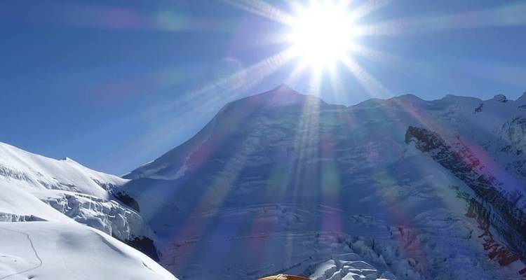 Felle zon die schijnt over besneeuwde bergen.