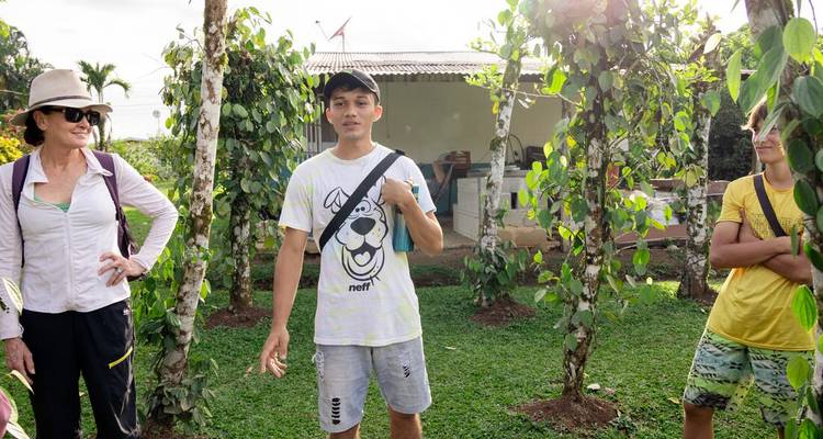 A small group of people outdoors near a house and greenery.