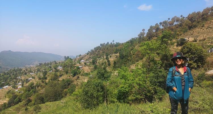 Person standing in a hilly landscape in Nepal with scattered houses and trees.