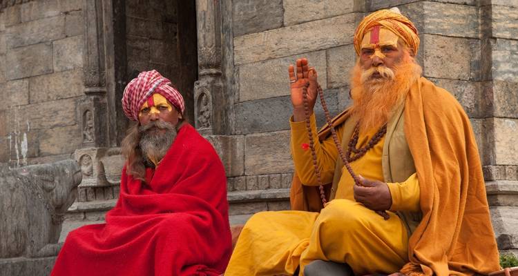 Twee wijzen in traditionele gewaden zittend buiten een tempel.