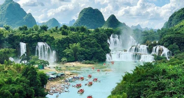 Ein großer Wasserfall mit Bergen im Hintergrund und mehreren Flößen auf dem Wasser.