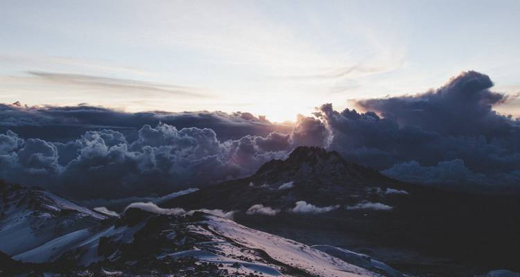 Atardecer sobre una montaña con nubes.