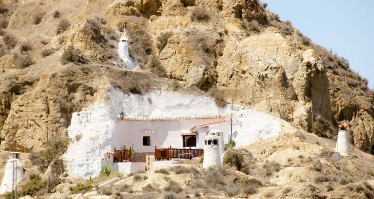 Whitewashed cave house built into a rugged cliff near Guadix on a sunny day