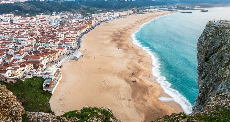 Vue aérienne d'une longue plage de sable avec une ville côtière.