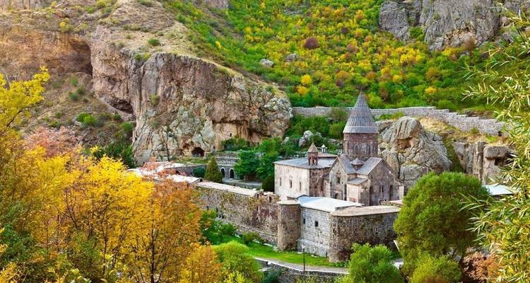 Ancient monastery nestled in lush mountainous surroundings.