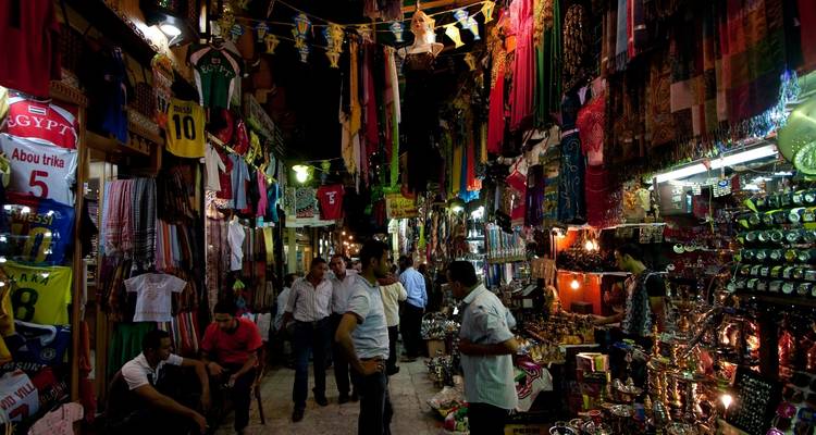 Eine belebte Marktstraße mit Geschäften, die bunte Textilien und Waren ausstellen.