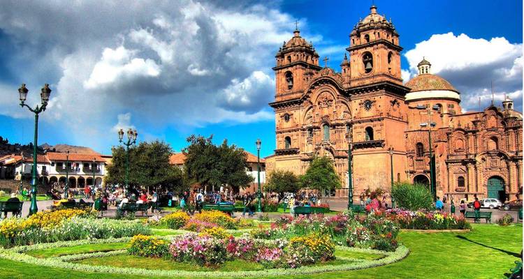 Plaza con jardín y catedral ornamentada.