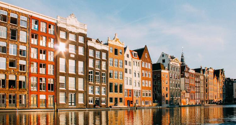 Canal d'Amsterdam avec des bâtiments colorés se reflétant dans l'eau.
