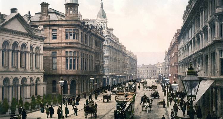 Vintage-Szenerie einer belebten Stadtstraße mit Pferdefuhrwerken und historischen Fassaden.