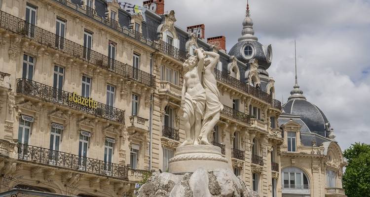 Edificios ornamentados de estilo Haussmann y una estatua de fuente en la Plaza de la Comedia de Montpellier.