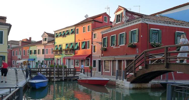 Colorful houses and small boats along a quiet canal in Burano, Venice’s vibrant island village.