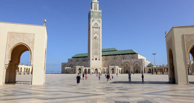 Wide plaza framing the Hassan II Mosque’s towering minaret and arched gateways under a clear blue sky.