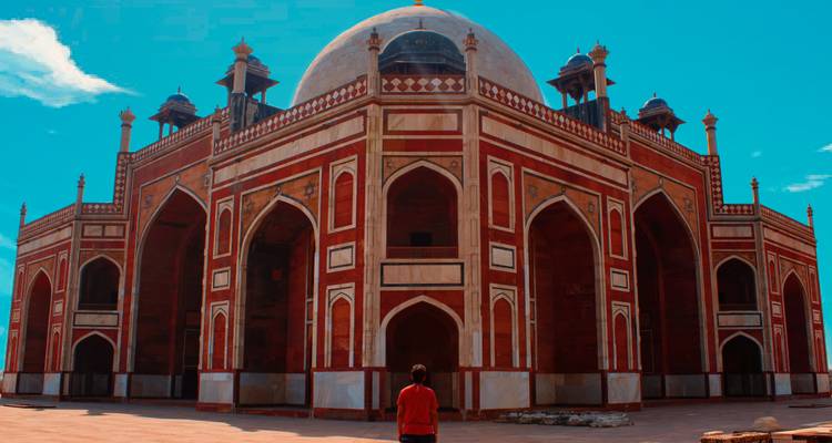 Person im roten Hemd vor einem historischen Mausoleum.