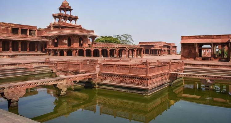 Les pavillons complexes en grès rouge et les bassins réfléchissants de Fatehpur Sikri par une journée dégagée.
