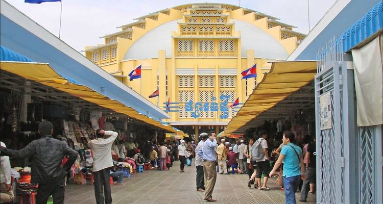 Een bruisende buitenmarkt met winkelende mensen en een architecturale achtergrond.