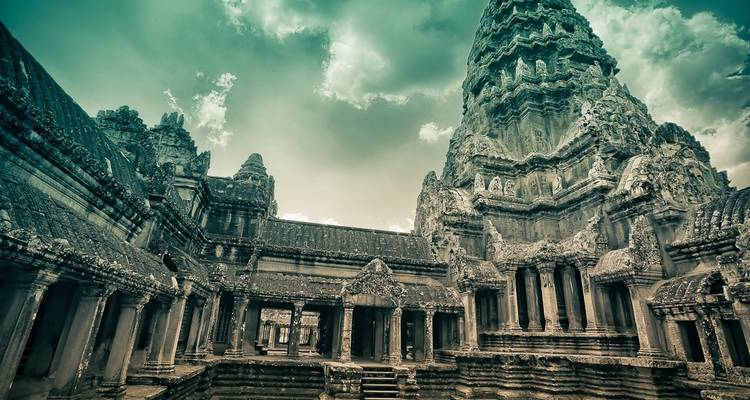 Oude stenen tempelruïnes met ingewikkelde gravures en een bewolkte hemel.