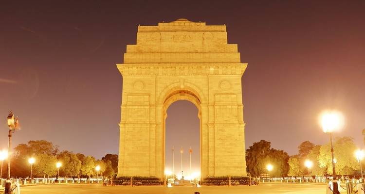 Monument en arc illuminé la nuit avec éclairage public.