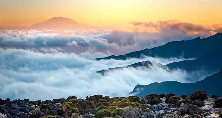Met sneeuw bedekte bergtoppen boven de wolken bij zonsopgang.