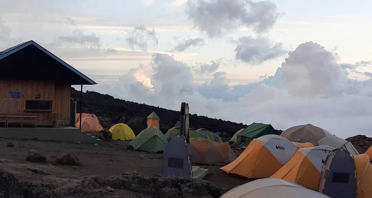Zeltplatz mit bunten Zelten inmitten einer bewölkten Berglandschaft.