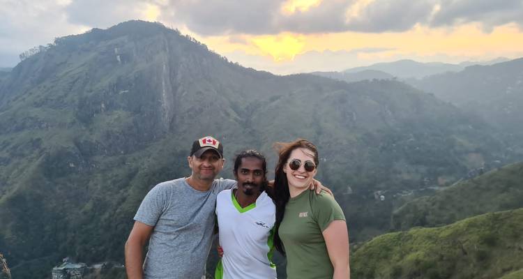 Tres personas posando con un fondo de montañas al atardecer.