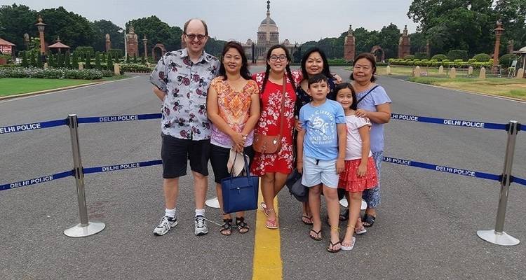Group of people posing by a road barrier near a historic building.