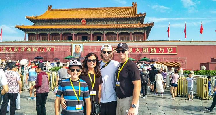 Una familia sonriente posa frente a la Puerta de Tiananmen con el retrato de Mao en medio de la multitud bulliciosa.