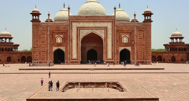 Mosquée du Taj Mahal avec du grès rouge et des incrustations de marbre blanc, entourée de touristes.