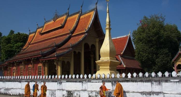 Monjes caminando junto a un templo con una estupa.