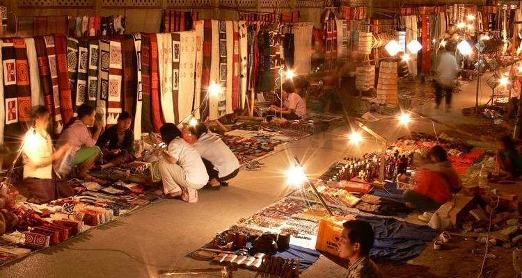Escena nocturna concurrida de mercado con varios puestos.