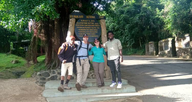 Eine Gruppe von Menschen posiert vor dem Schild des Kilimanjaro National Park.