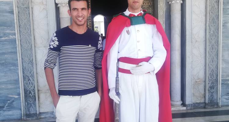 Dos hombres posando frente a una entrada arqueada de diseño ornamentado.