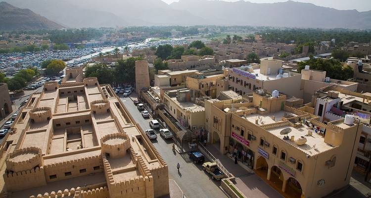 Vista aérea de un pueblo tradicional omaní con montañas al fondo.