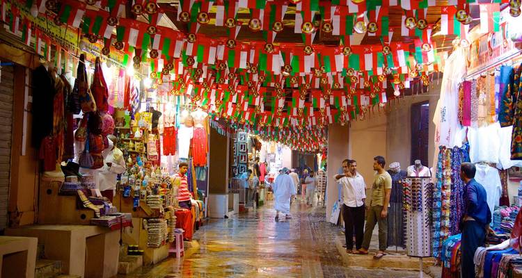Calle de mercado vibrante en Omán decorada con banderas nacionales.