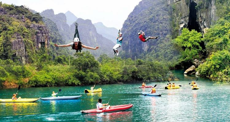 Mensen die ziplinen en kajakken op een rivier omgeven door rotswanden.