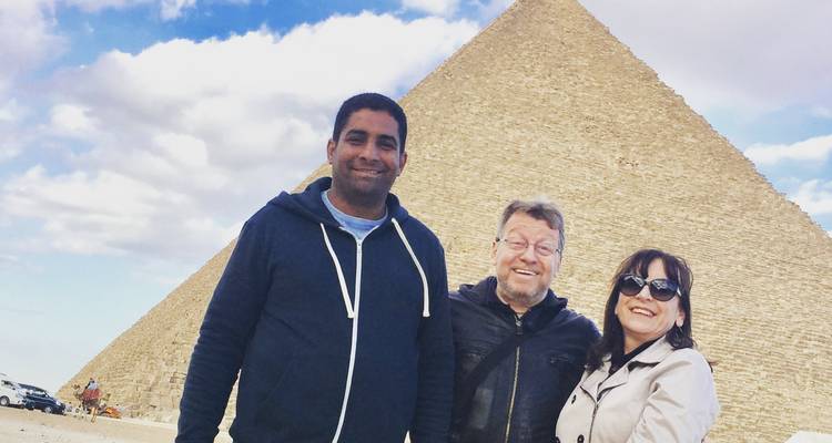 Drie mensen poseren voor een piramide.